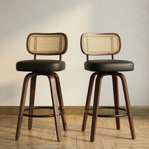 Könnte beinhalten: Zwei Barhocker mit dunklen Holzrahmen, schwarzen Ledersitzen und gewebten Rohrgeflecht-Rückenlehnen. Die Hocker haben eine Fußstütze aus schwarzem Metall und ein modernes Design. Geeignet für Küche oder Bar.