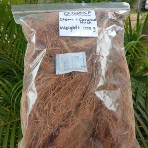 May include: A clear plastic bag filled with brown coconut husk. The bag has a zip closure and a white label with the text "Item: Coconut Husk" and "Weight: 100 g". A small packet of silica gel is inside the bag.