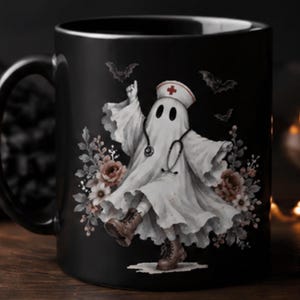 May include: A black ceramic mug featuring a graphic of a white ghost dressed as a nurse, complete with a stethoscope, a nurse cap with a red cross, and brown boots. The ghost is surrounded by floral accents and small bats on a dark background.