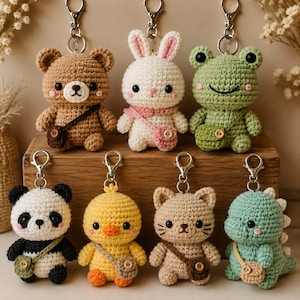 May include: A collection of seven crocheted animal keychains featuring a brown bear, white rabbit, green frog, black and white panda, yellow chick, tan cat, and light green dinosaur. Each plush figure includes a small crossbody bag and metal clasp.
