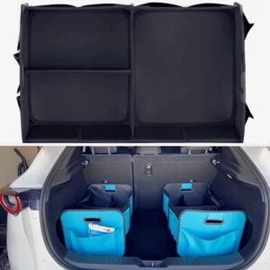 May include: Black car boot organiser with multiple compartments. Below, two blue storage bins with pockets are placed in a car boot. The bins have a handle and are designed to keep items organised. The car is white.