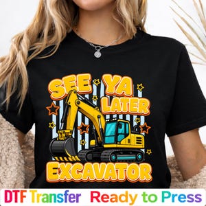 May include: A black t-shirt featuring a graphic of a yellow excavator with black tracks. The text "SEE YA LATER EXCAVATOR" is printed in bold yellow letters above and below the construction vehicle, surrounded by orange and yellow stars.