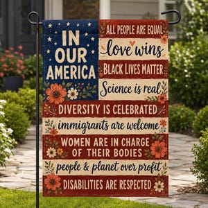 Könnte beinhalten: Eine Gartenflagge mit patriotischem Design. Die Flagge zeigt den Text "IN OUR AMERICA" auf blauem Hintergrund mit weißen Sternen. Die Flagge enthält auch die Sätze "ALL PEOPLE ARE EQUAL", "love wins", "BLACK LIVES MATTER", "Science is real", "DIVERSITY IS CELEBRATED", "immigrants are welcome", "WOMEN ARE IN CHARGE OF THEIR BODIES", "people & planet over profit" und "DISABILITIES ARE RESPECTED".