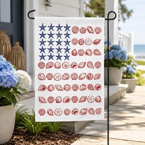 May include: A rectangular garden flag featuring a white background with a patriotic design. The upper left corner displays blue starfish arranged in a grid, while the remaining area features rows of red seashells and sand dollars in a flag pattern.