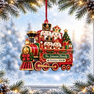 May include: A red and gold Christmas train ornament featuring four nutcracker figures, a decorated pine tree, and gifts. The side of the train displays the text The Johnson Family and Christmas 2026. It hangs from a thin red ribbon.