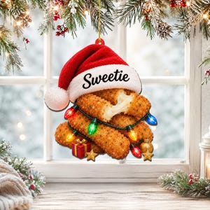May include: A hanging ornament shaped like a stack of breaded mozzarella sticks topped with a red and white Santa hat featuring the text Sweetie. The sticks are wrapped in a string of colourful Christmas lights with small gift and star accents.