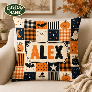 May include: A square throw pillow featuring a patchwork design with Halloween motifs including orange pumpkins, white ghosts, black bats, stars, and plaid patterns. The centre displays a cream-coloured label with the name ALEX in orange and black.