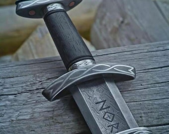 May include: A sword with a dark wooden handle and a silver-colored pommel and crossguard featuring intricate knotwork patterns. The metal blade displays a visible Damascus steel texture and is engraved with the letters NOR in a runic style.