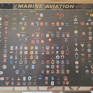 May include: A rectangular poster titled Marine Aviation 1995 featuring a dark gray background with a grid of numerous small, colorful military unit patches and emblems organized into categories including Regular and Reserve units.