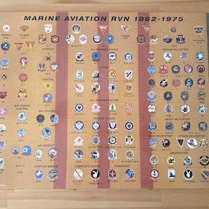 May include: A rectangular poster titled Marine Aviation RVN 1962-1975 featuring a grid of numerous small circular and triangular military unit patches arranged by category, including All Weather Attack, Fighter Attack, and Helicopter squadrons.