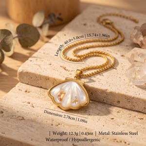 May include: A gold-toned stainless steel necklace featuring a shell-shaped pendant with a white iridescent inlay, a small gold starfish, and a tiny gold accent. The chain length is 15.74 inches plus a 1.96 inch extender, weighing 0.43 ounces total.
