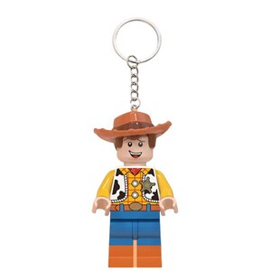 Puede incluir: Un llavero con una figura de vaquero de pl&aacute;stico que lleva un sombrero marr&oacute;n, una camisa de cuadros amarilla con un chaleco de manchas blancas y negras, una estrella de sheriff plateada, pantalones azules y botas marrones, unido a una argolla.