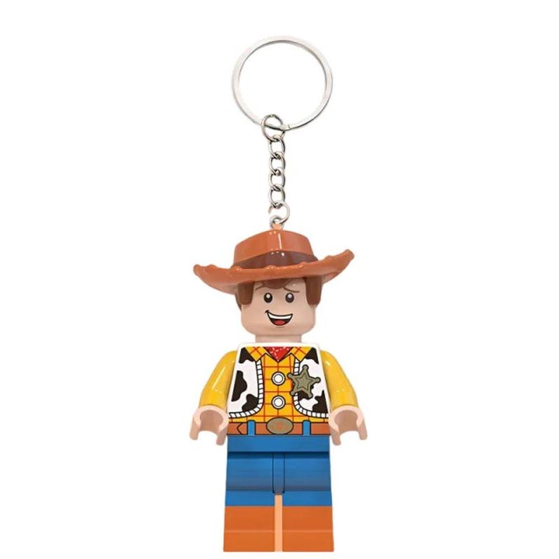 Puede incluir: Un llavero con una figura de vaquero de pl&aacute;stico que lleva un sombrero marr&oacute;n, una camisa de cuadros amarilla con un chaleco de manchas blancas y negras, una estrella de sheriff plateada, pantalones azules y botas marrones, unido a una argolla.