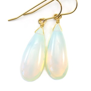 May include: A pair of gold teardrop earrings with iridescent opal stones.