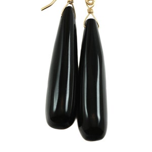 May include: A pair of black teardrop-shaped earrings with gold hooks.