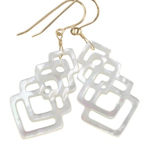 May include: White mother of pearl earrings with a geometric design. The earrings are made of multiple layers of mother of pearl that are cut into a square shape with a geometric pattern. The earrings are attached to gold hooks.