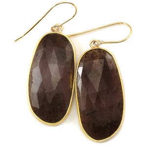 May include: A pair of gold earrings with large, oval-shaped, faceted, dark brown gemstones.