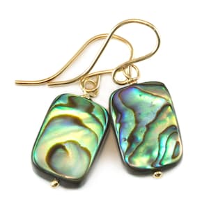 May include: A pair of gold earrings with iridescent green and blue abalone shell rectangular pendants.