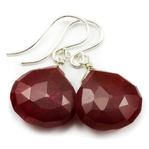 May include: A pair of silver dangle earrings with faceted ruby red gemstone drops.