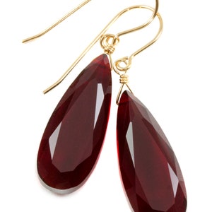 Peut inclure: Une paire de boucles d'oreilles en or avec des pendentifs en forme de goutte de pierre précieuse rouge.