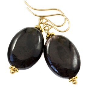 Peut inclure: Une paire de boucles d'oreilles en pierre noire avec des crochets et des accents dorés. Les boucles d'oreilles sont de forme ovale et ont une finition lisse et polie.
