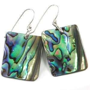 May include: A pair of square abalone shell earrings with sterling silver ear wires. The earrings display iridescent colors of green, blue, and purple. The abalone shells have a polished, glossy finish, reflecting light.