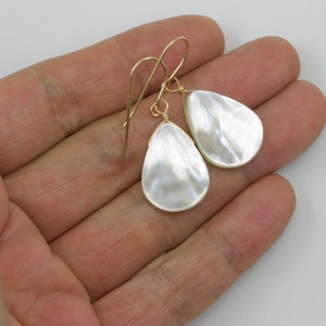 May include: A pair of gold teardrop earrings with white mother of pearl stones.