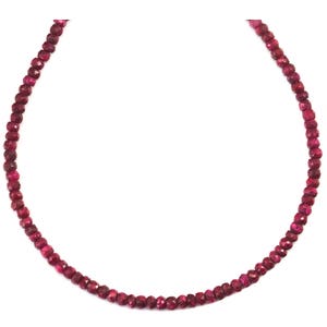 May include: A necklace made of small, faceted ruby beads. The beads are a deep red color and are strung on a thin silver chain.