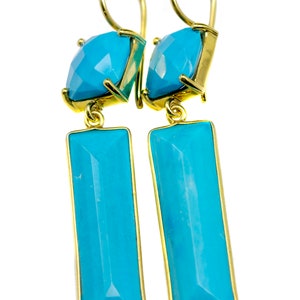 May include: A pair of gold earrings with turquoise stones. The earrings have a square stone at the top and a rectangular stone hanging below.
