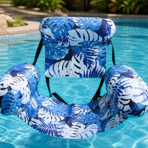Peut inclure: Un fauteuil de piscine gonflable bleu et blanc avec un motif de feuilles tropicales. Le fauteuil est équipé d'un dossier et d'accoudoirs, et flotte dans une piscine. Il est conçu pour une utilisation dans l'eau.