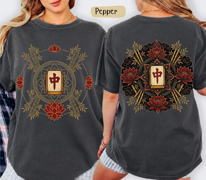 May include: Dark grey t-shirt with a front and back design. The front features a gold and red graphic with bamboo, lotus flowers, and a central tile. The back design is similar.