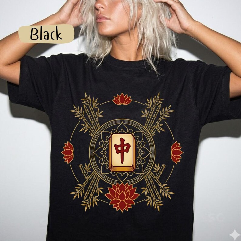 May include: Black t-shirt with a gold and red graphic. The design features bamboo, lotus flowers, and a central tile with Chinese characters. The word "Black" is printed on a tan label.
