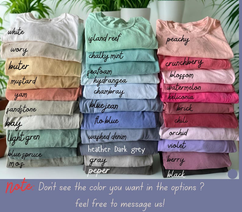 May include: A selection of stacked t-shirts in a variety of colours, such as white, ivory, and mustard. Other colours include island reef, chalky mint, peachy, and crunchberry. The image also includes text that says "note: Don't see the colour you want in the options? feel free to message us!"