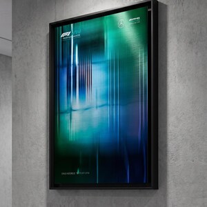 Puede incluir: Un cuadro rectangular enmarcado con un degradado vertical de azul, verde azulado y negro con rayas de luz. La impresión muestra el logotipo F1 W14 Performance, la estrella de Mercedes-Benz, el logotipo de AMG Petronas y el texto Engineered to Perform.