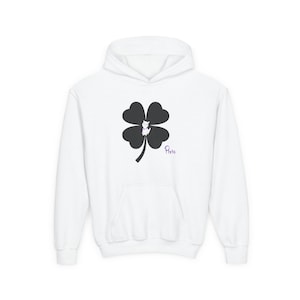 May include: White hoodie featuring a black four-leaf clover design with a small white cat wearing a pink bow. The word "Paris" is written in purple script on the lower right side of the hoodie. The hoodie has a front pocket and a hood.