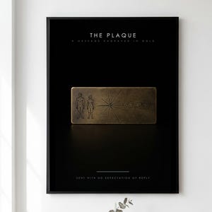 May include: A framed black poster featuring a gold-toned rectangular plaque with engraved line art of two human figures, a pulsar map, and a solar system diagram. The text reads THE PLAQUE, A MESSAGE ENGRAVED IN GOLD, and SENT WITH NO EXPECTATION OF REPLY.