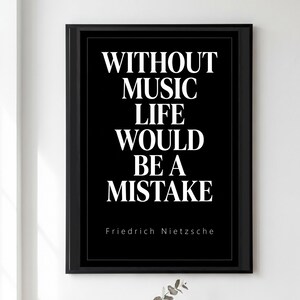 Puede incluir: Un cuadro rectangular con marco negro que presenta el texto en blanco: WITHOUT MUSIC LIFE WOULD BE A MISTAKE, seguido por el nombre Friedrich Nietzsche en letras blancas más pequeñas en la parte inferior de la impresión.