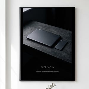 May include: A framed wall art print featuring a black laptop and a smartphone placed face down on a dark wooden surface. The text DEEP WORK is printed in white, followed by the sentence The phone face down is the whole technique.