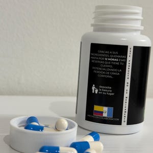 K&ouml;nnte beinhalten: Wei&szlig;e Plastikflasche mit einem schwarzen Etikett, das blau-wei&szlig;e Kapseln enth&auml;lt. Das Etikett hat Text auf Spanisch. Der Deckel der Flasche ist abgenommen und zeigt weitere Kapseln. Die Kapseln sind um die Kappe verstreut.