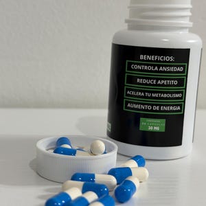 K&ouml;nnte beinhalten: Eine wei&szlig;e Plastikflasche mit einem schwarzen Etikett, das Vorteile auf Spanisch auflistet, darunter Angstkontrolle und erh&ouml;hte Energie. Blaue und wei&szlig;e Kapseln sind um die Flasche und im Deckel verstreut. Die Flasche enth&auml;lt 30 Kapseln, 30 mg.