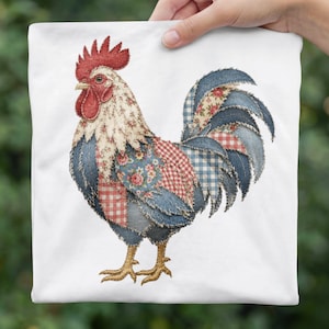 May include: A white square pillow featuring a colorful rooster design. The rooster is made of patchwork denim and floral fabrics, with a red comb and wattle. The pillow is held by a hand against a blurred green background.