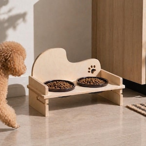 Pode incluir: Um comedouro de madeira clara para animais de estimação com duas tigelas redondas cheias de comida. O comedouro tem um desenho de pegada e está ao lado de um poodle castanho. O comedouro tem aproximadamente 30 cm de largura.