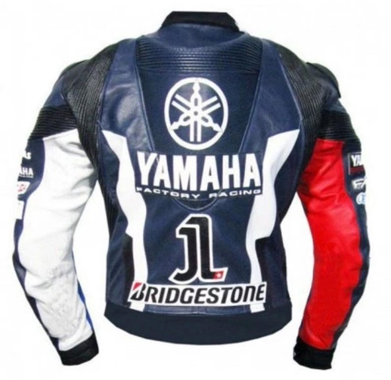 Pode incluir: Casaco de motociclismo em couro Yamaha Factory Racing azul marinho e branco com detalhes em vermelho e branco. O casaco apresenta o log&oacute;tipo Yamaha, o n&uacute;mero 1 e a marca Bridgestone.
