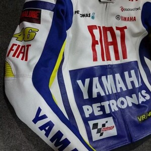 May include: A white, blue, and yellow motorcycle racing jacket featuring prominent branding including Fiat, Yamaha, Petronas, and the number 46. The jacket displays various sponsor logos such as Packard Bell, Fast Web, and the MotoGP emblem on the front.