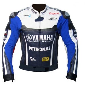 Pode incluir: Uma jaqueta de motocicleta Yamaha Factory Racing em branco, azul e preto. A jaqueta apresenta o logotipo da Yamaha, a marca Petronas e a marca Xlite. Possui z&iacute;per frontal, ombros acolchoados e gola alta. As mangas s&atilde;o azuis com listras brancas.