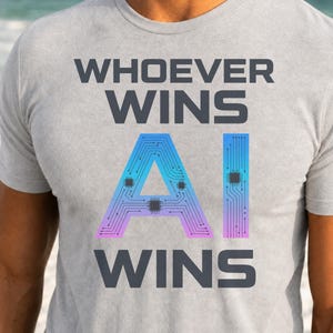 May include: A light grey t-shirt featuring the dark grey text WHOEVER WINS at the top and WINS at the bottom. In the centre, the letters AI are displayed in a blue to purple gradient, decorated with a black circuit board pattern and small chips.