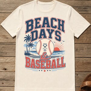 May include: A cream-colored short-sleeve t-shirt featuring a graphic print with the text BEACH DAYS & BASEBALL. The design includes a baseball, palm trees, a sun, and ocean waves in red, blue, and white colors, with USA EST. 1987 on the ball.