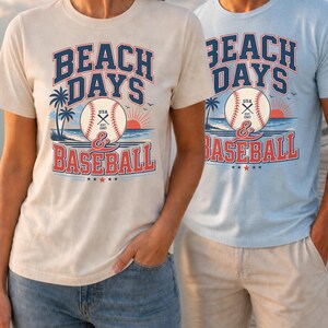 May include: A cream-colored t-shirt and a light blue t-shirt, both featuring a graphic print that reads BEACH DAYS & BASEBALL. The design includes a baseball with USA EST 1997 text, palm trees, a sunset over the ocean, and small birds.