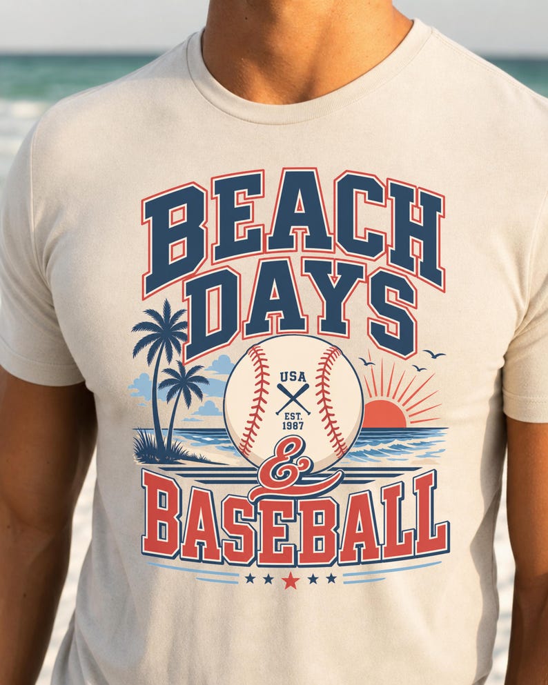 May include: A cream-colored short-sleeve t-shirt featuring a graphic print with the text BEACH DAYS & BASEBALL. The design includes a baseball, palm trees, a sunset over the ocean, and the text USA EST. 1987, rendered in navy blue and red.