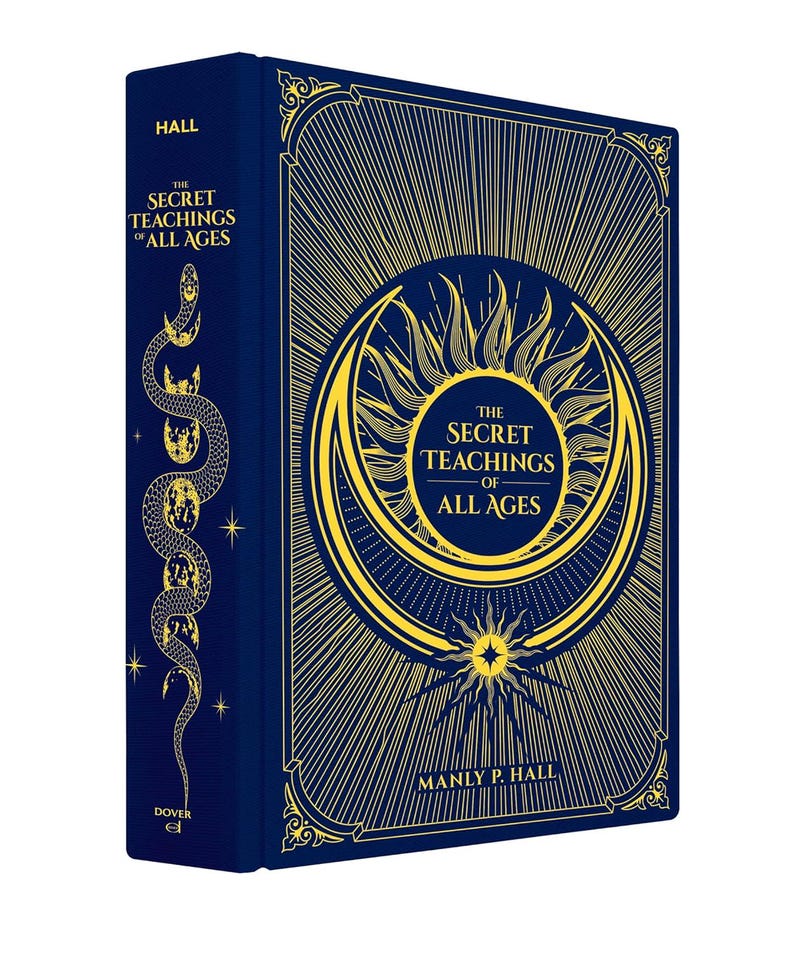Puede incluir: Un libro de tapa dura titulado "The Secret Teachings of All Ages" de Manly P. Hall. El libro tiene una cubierta azul oscuro con ilustraciones doradas en relieve, incluyendo un sol, una luna creciente y una serpiente. El lomo dice "Hall".